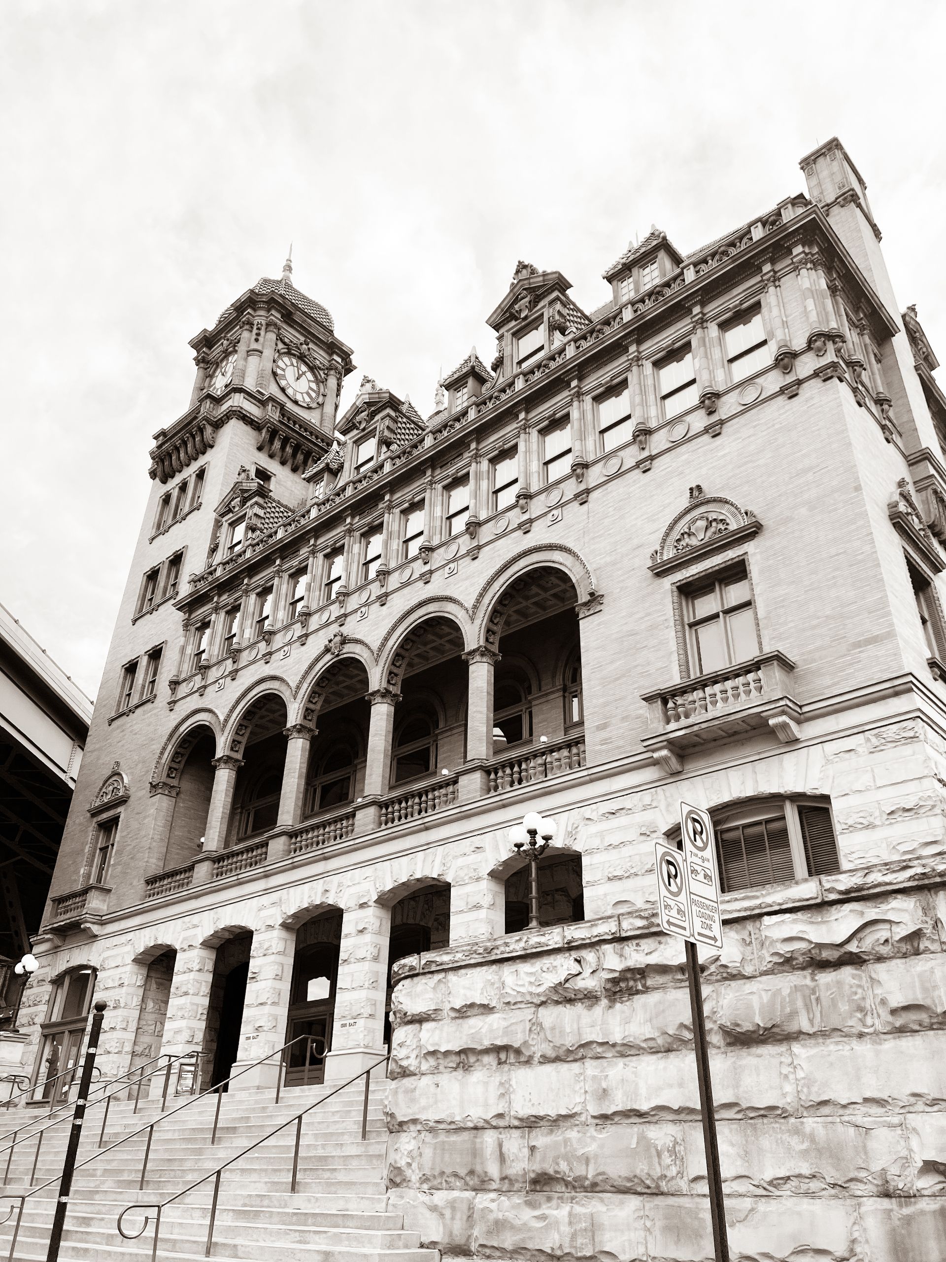 A black and white photo of a large building with stairs leading up to it.
