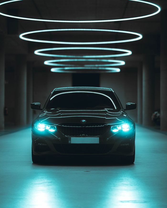 A car is parked in a dark garage with blue lights hanging from the ceiling