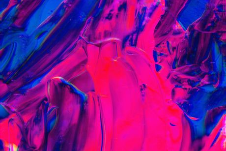 A close up of a pink and blue painting on a wall.