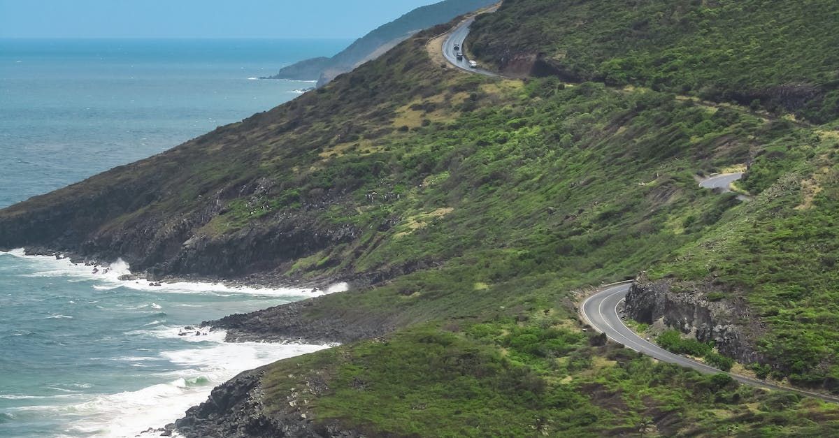 a road going down a hill next to the ocean .