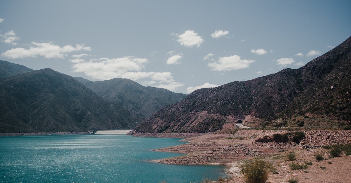 A large body of water surrounded by mountains on a sunny day.