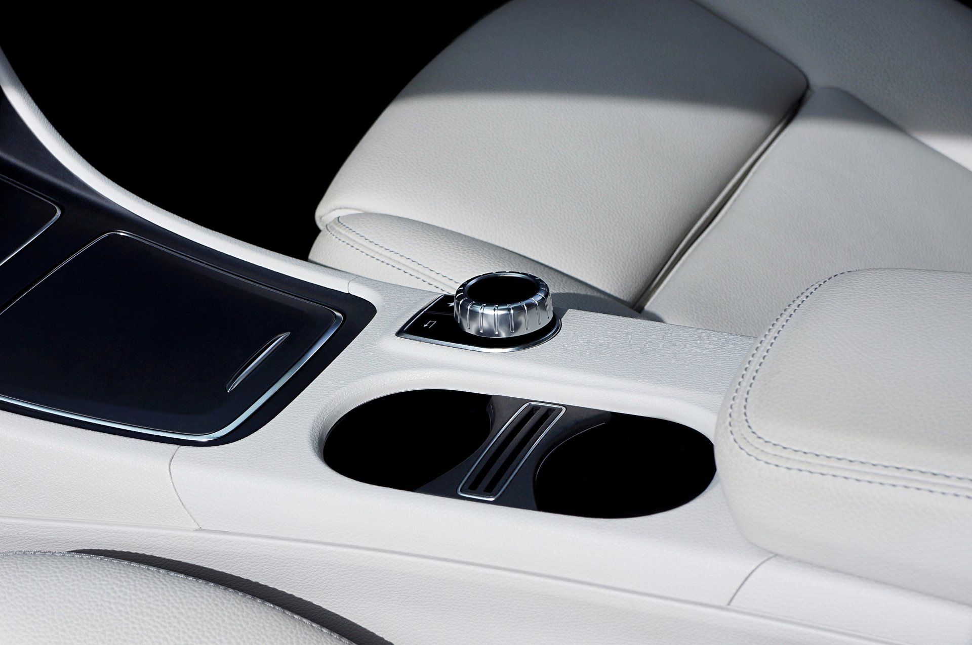 A car console with a cup holder and a control knob