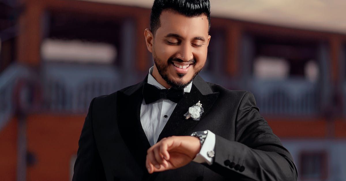 A man in a tuxedo is looking at his watch.