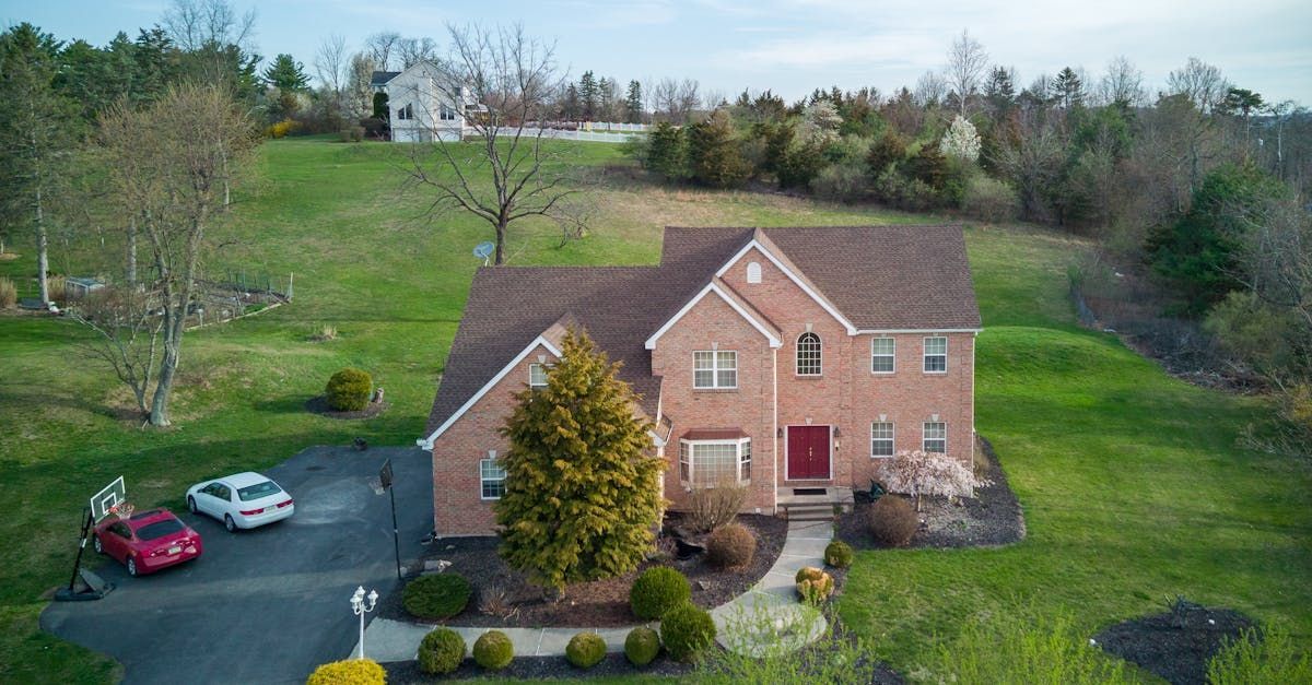 An aerial view of a large brick house surrounded by trees and grass.