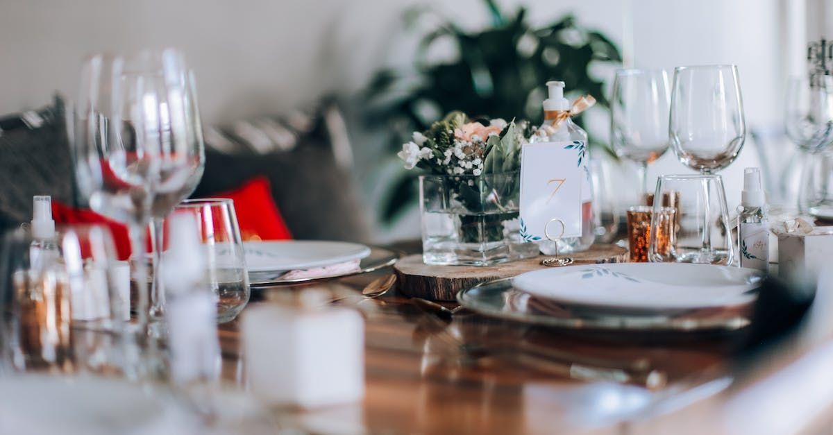 A table set for a dinner party with plates , wine glasses , and silverware.