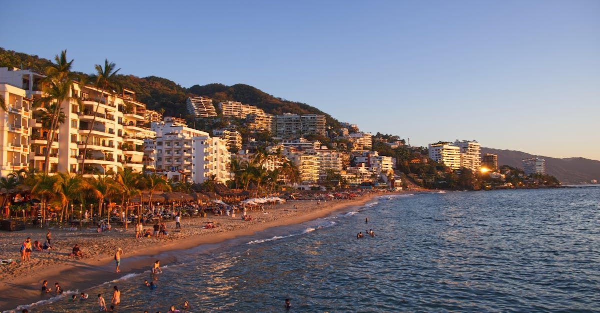 Una playa con mucha gente y edificios al fondo.