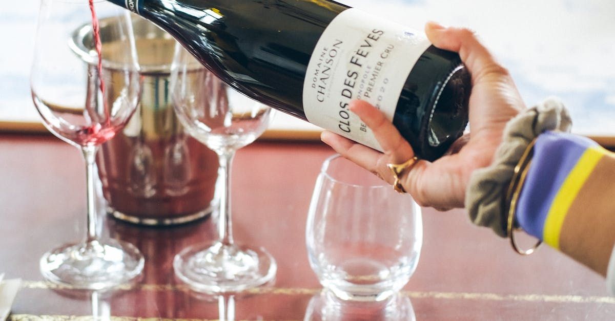 A person is pouring wine into a glass on a table.