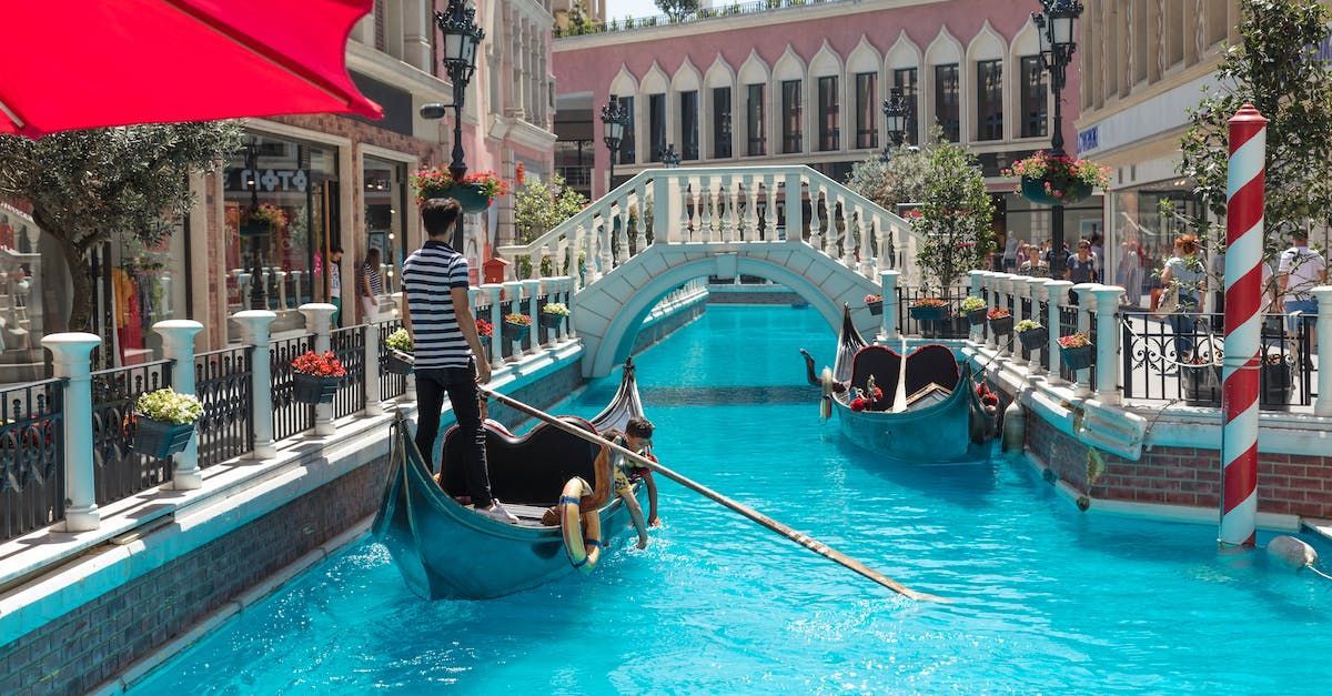 A man is riding a gondola down a canal.