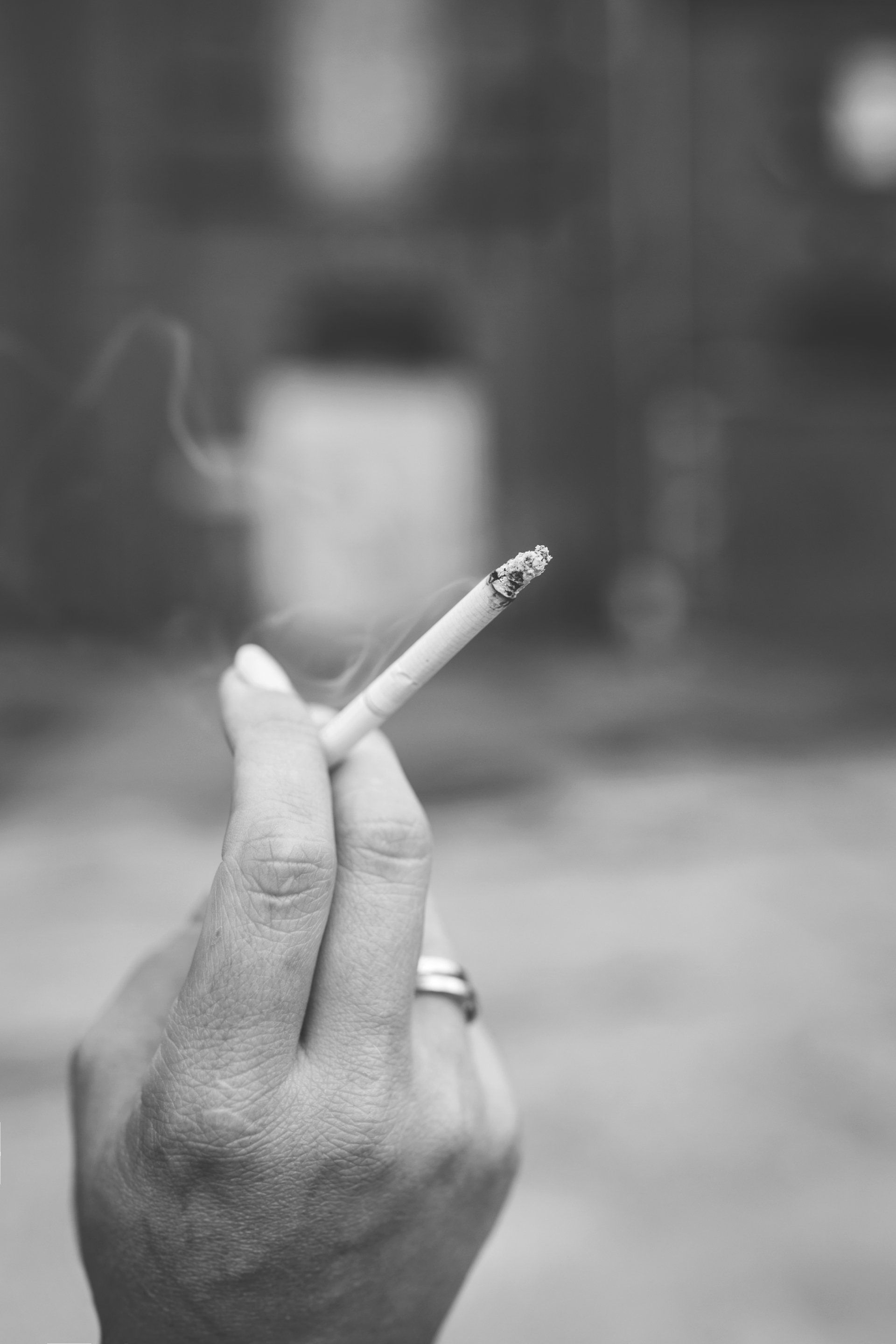 Close-up photo of a hand holding a lit cigarette. 
