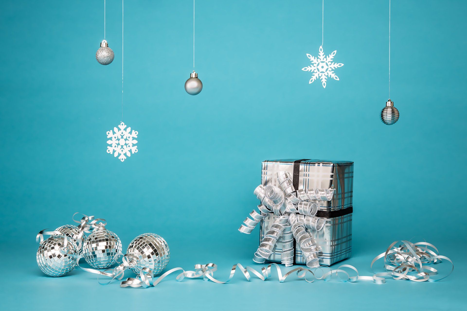 a blue background with silver christmas decorations hanging from the ceiling