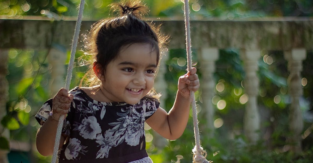 A little girl is sitting on a swing and smiling.