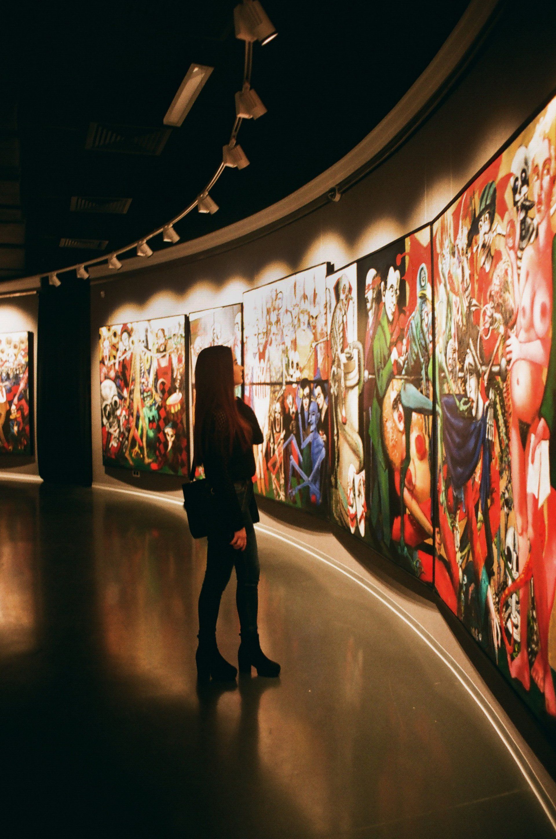 a woman is standing in front of a wall of paintings in a museum .