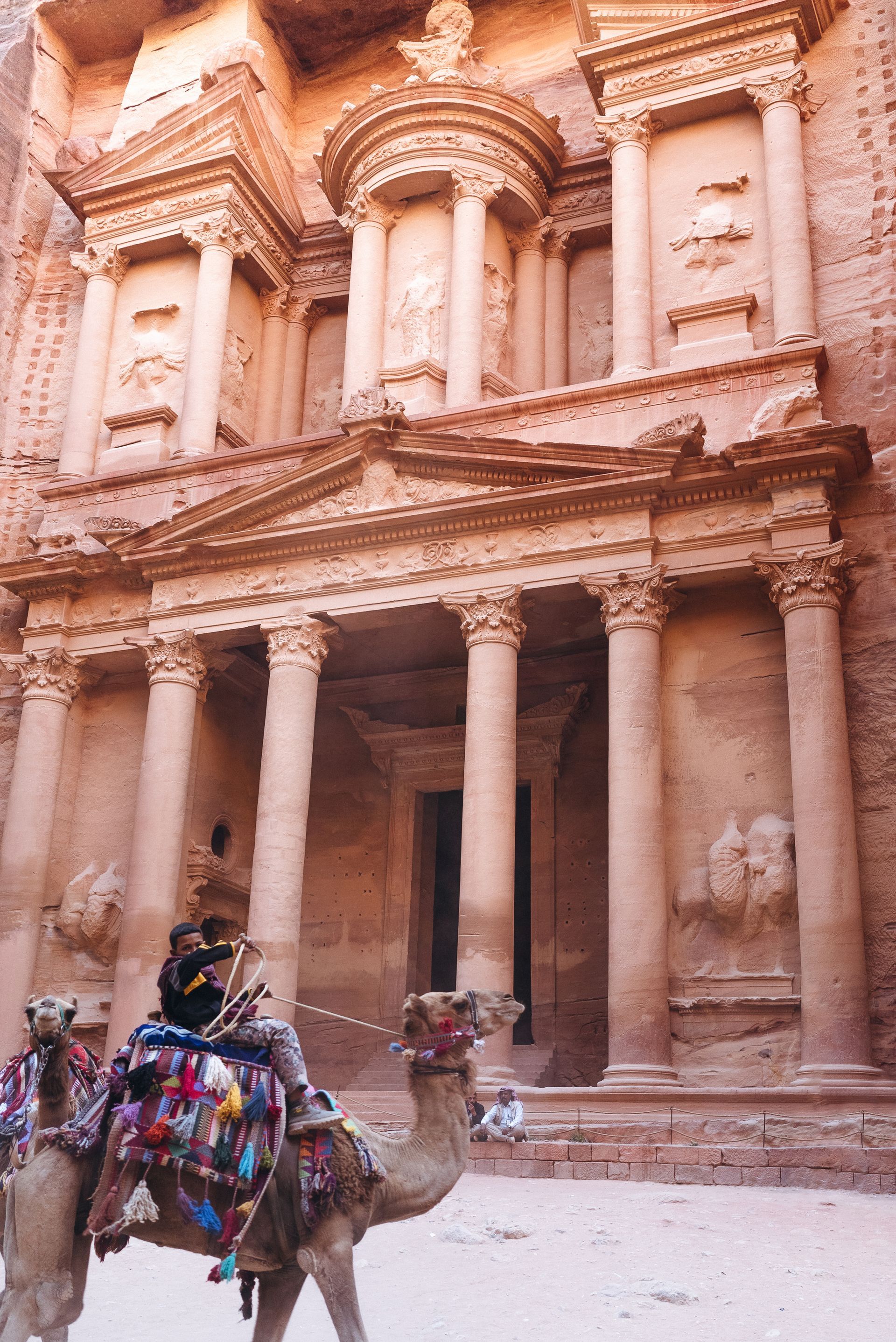 A person riding a camel in front of a large building