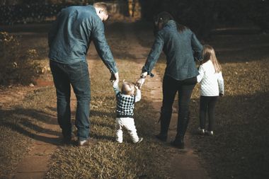 A family is walking down a path holding hands.