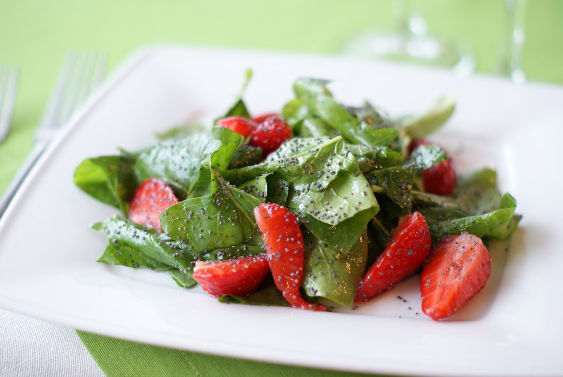 a white plate topped with strawberries and lettuce on a green table .