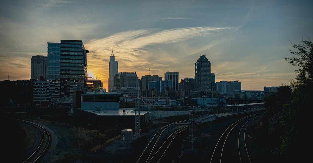 A city skyline at sunset with a train track in the foreground.