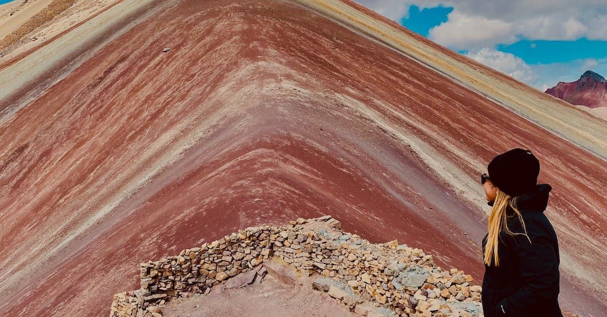 Una mujer está parada en la cima de una montaña colorida.