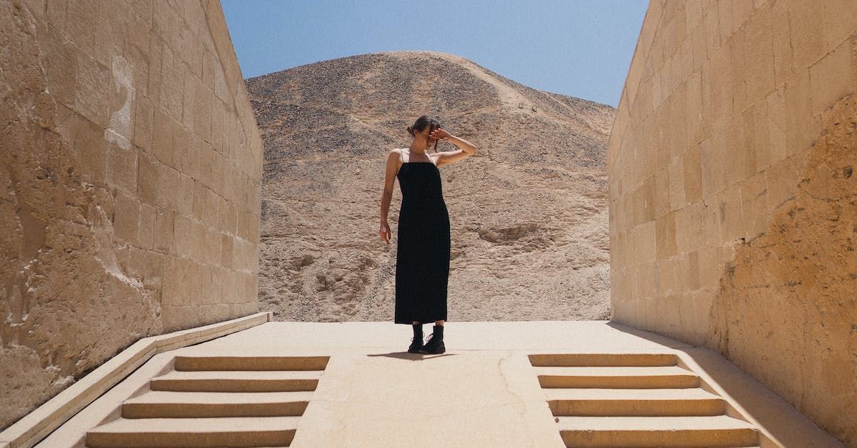 A woman in a black dress is standing in a tunnel in the desert.