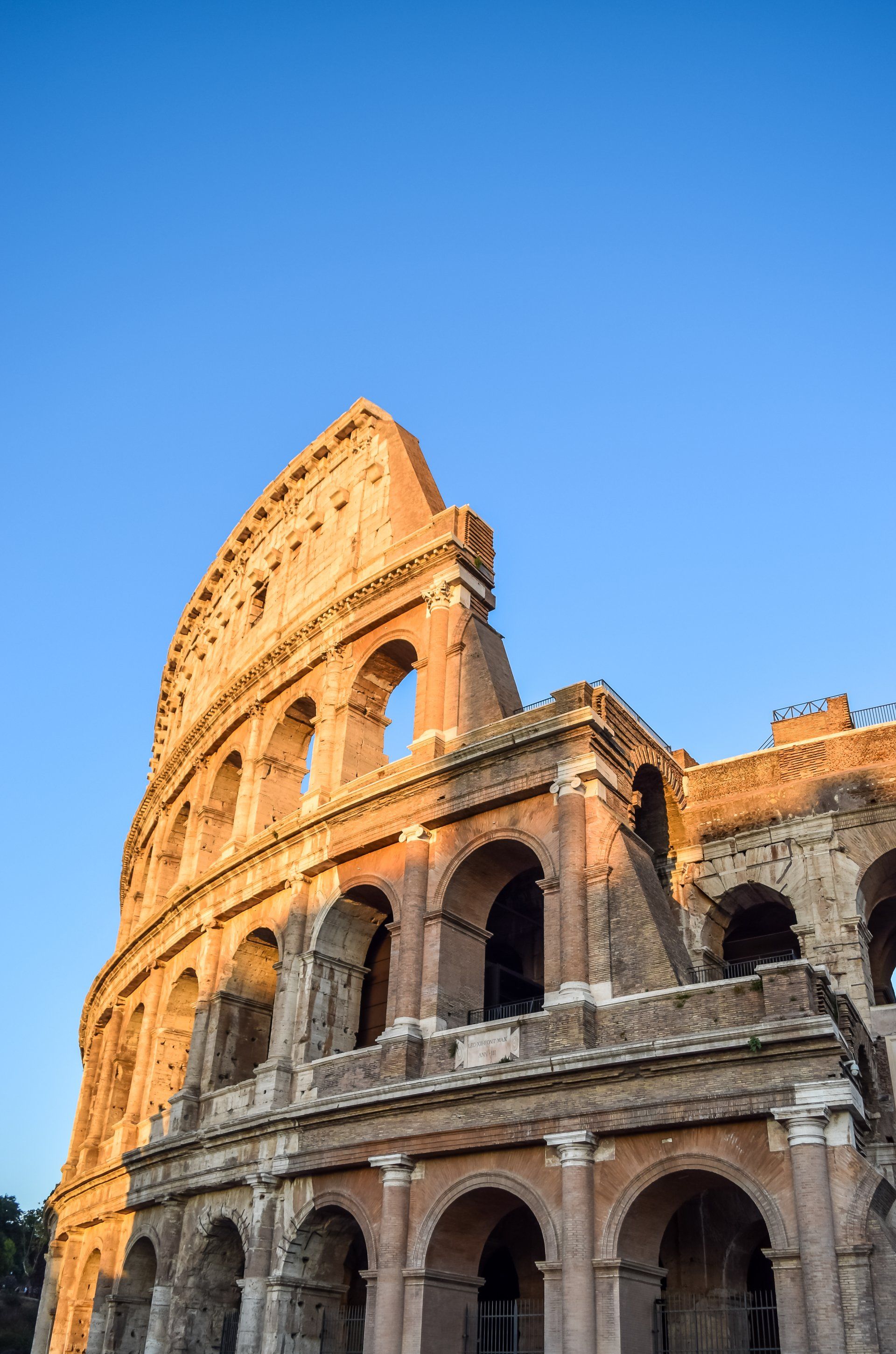 the colosseum in rome is a very tall building with a blue sky in the background .
