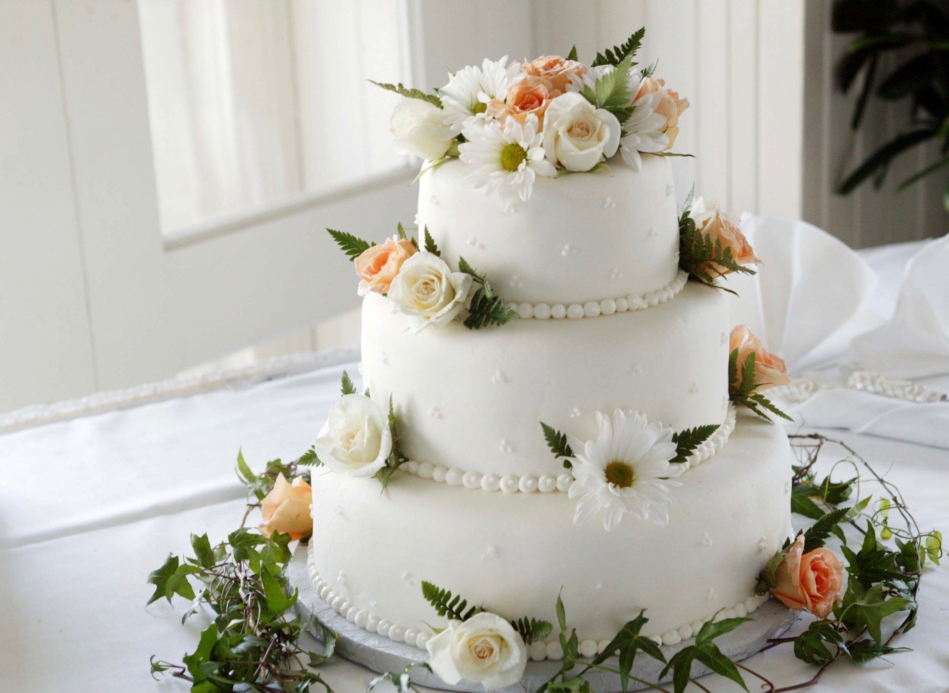 A three tiered wedding cake decorated with flowers and pearls