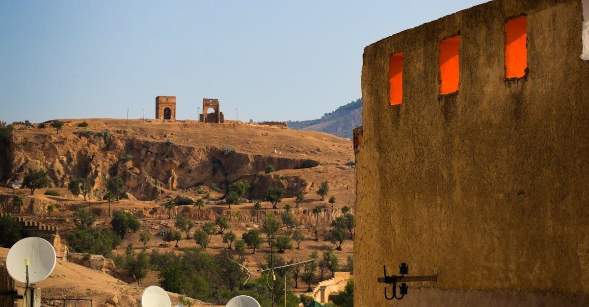 A desert landscape with a building in the foreground and satellite dishes in the background.