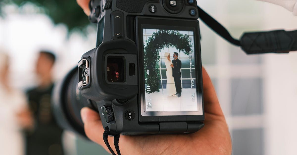 A person is taking a picture of a bride and groom with a camera.