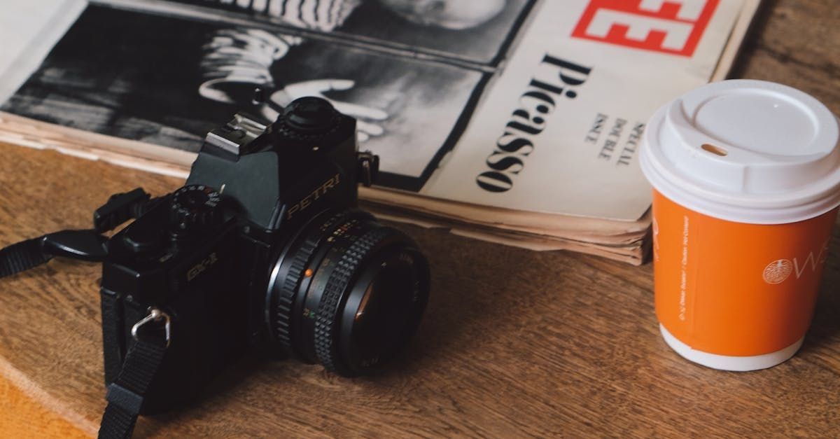 A camera is sitting on top of a newspaper next to a cup of coffee.