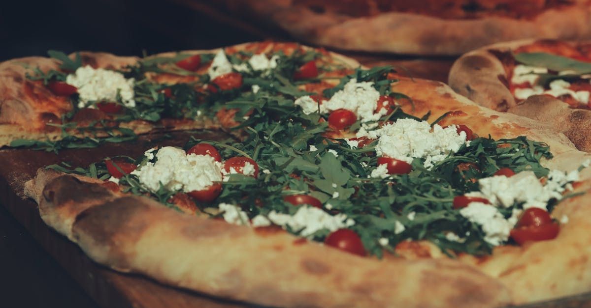 un primo piano di una pizza con pomodori e formaggio su un tavolo.