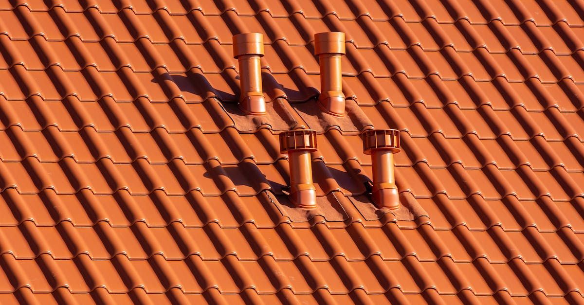 A close up of a tiled roof with chimneys on it.