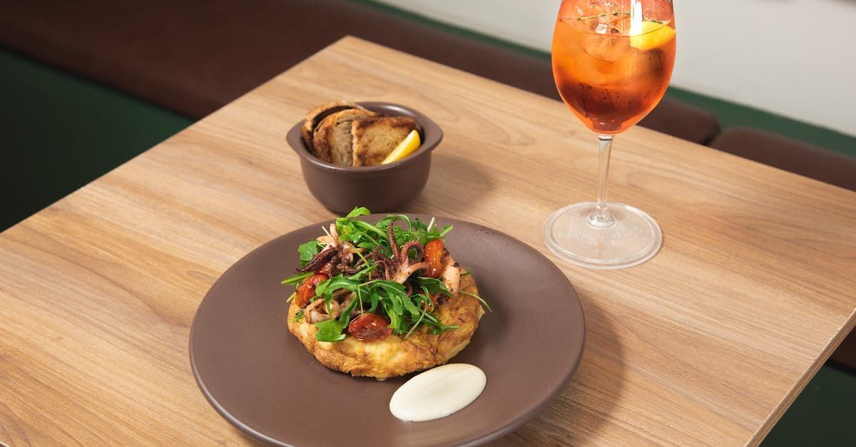 A plate of food and a glass of wine on a wooden table.