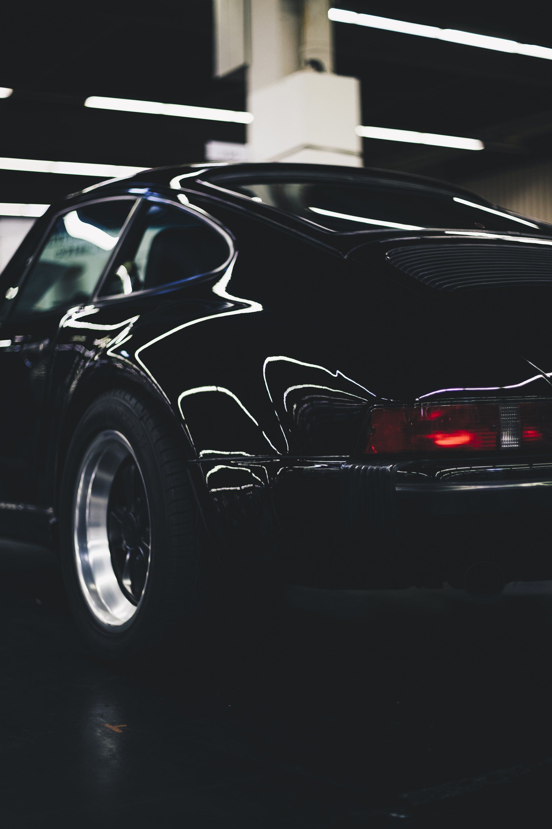 A black sports car is parked in a dark garage