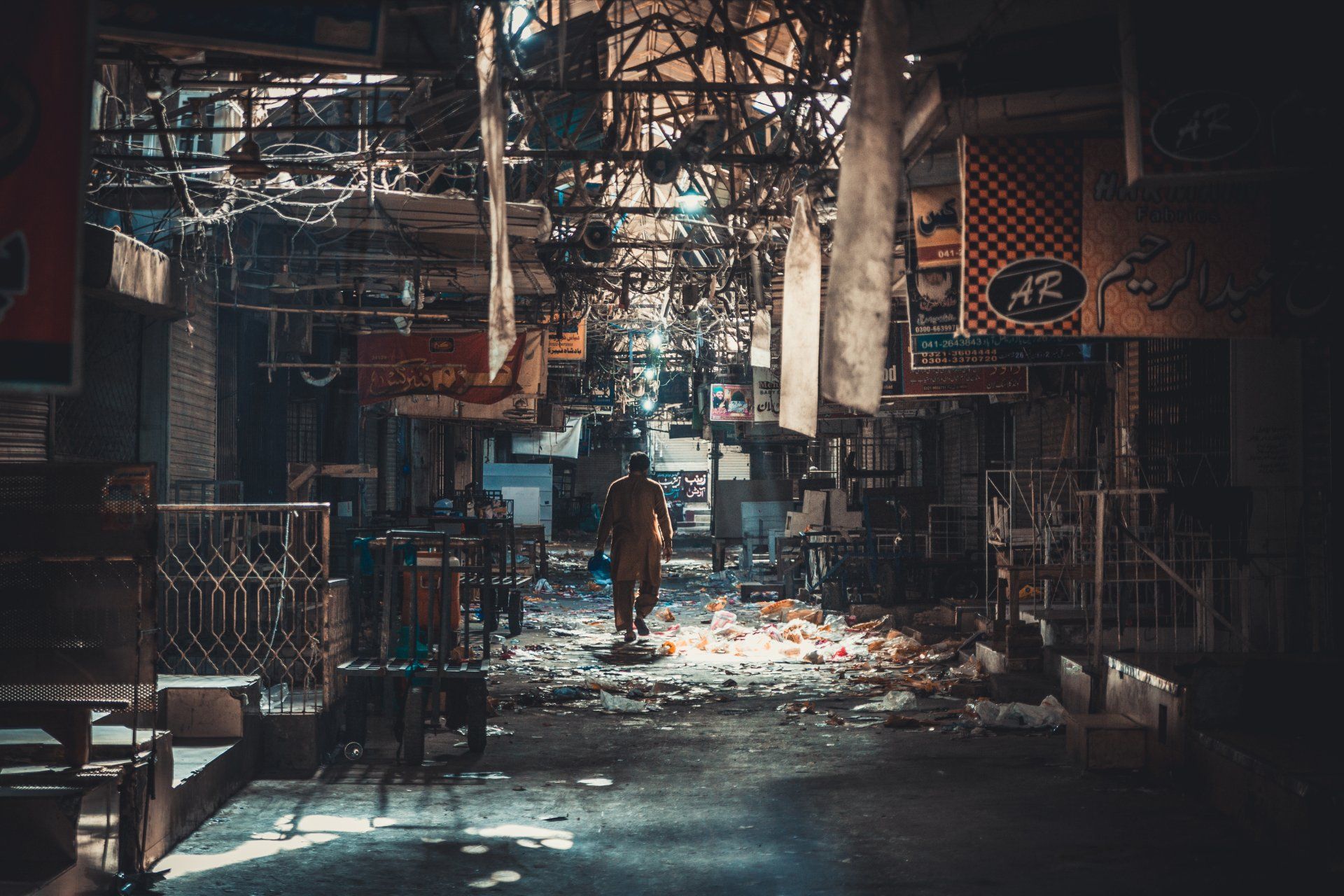 A business area with garbage all over the floors while a worker walks among it