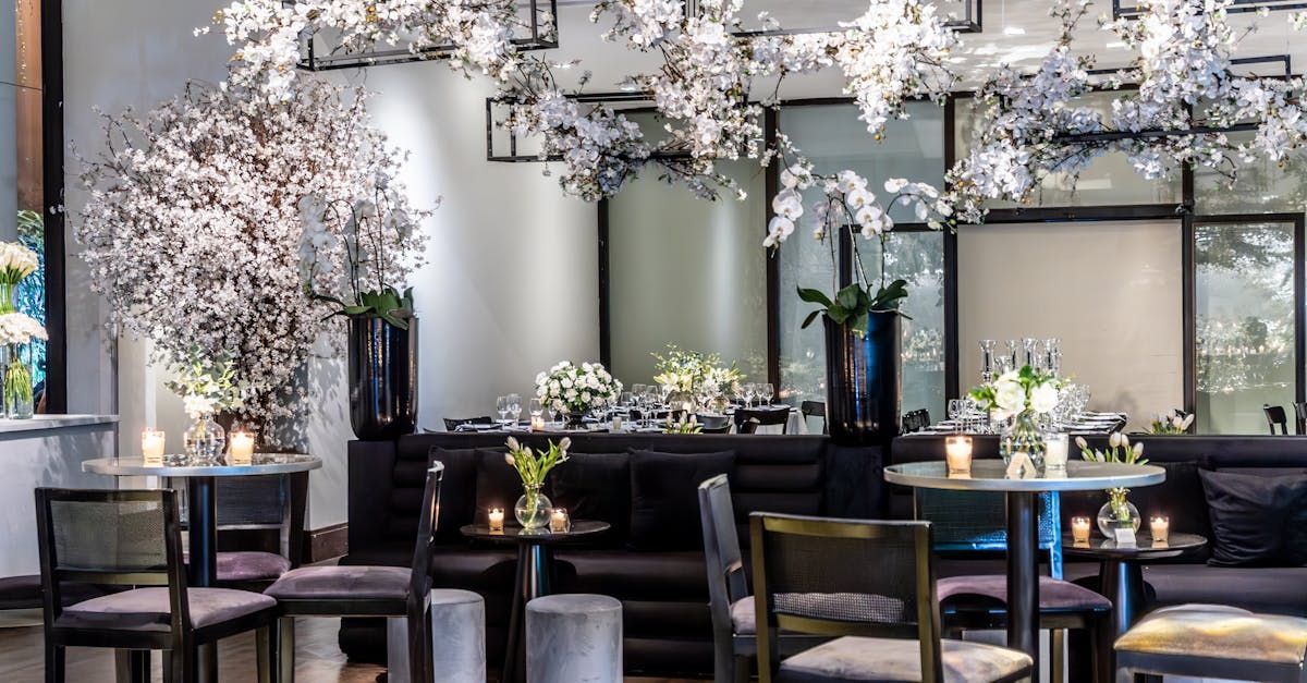A restaurant with tables and chairs and flowers hanging from the ceiling.