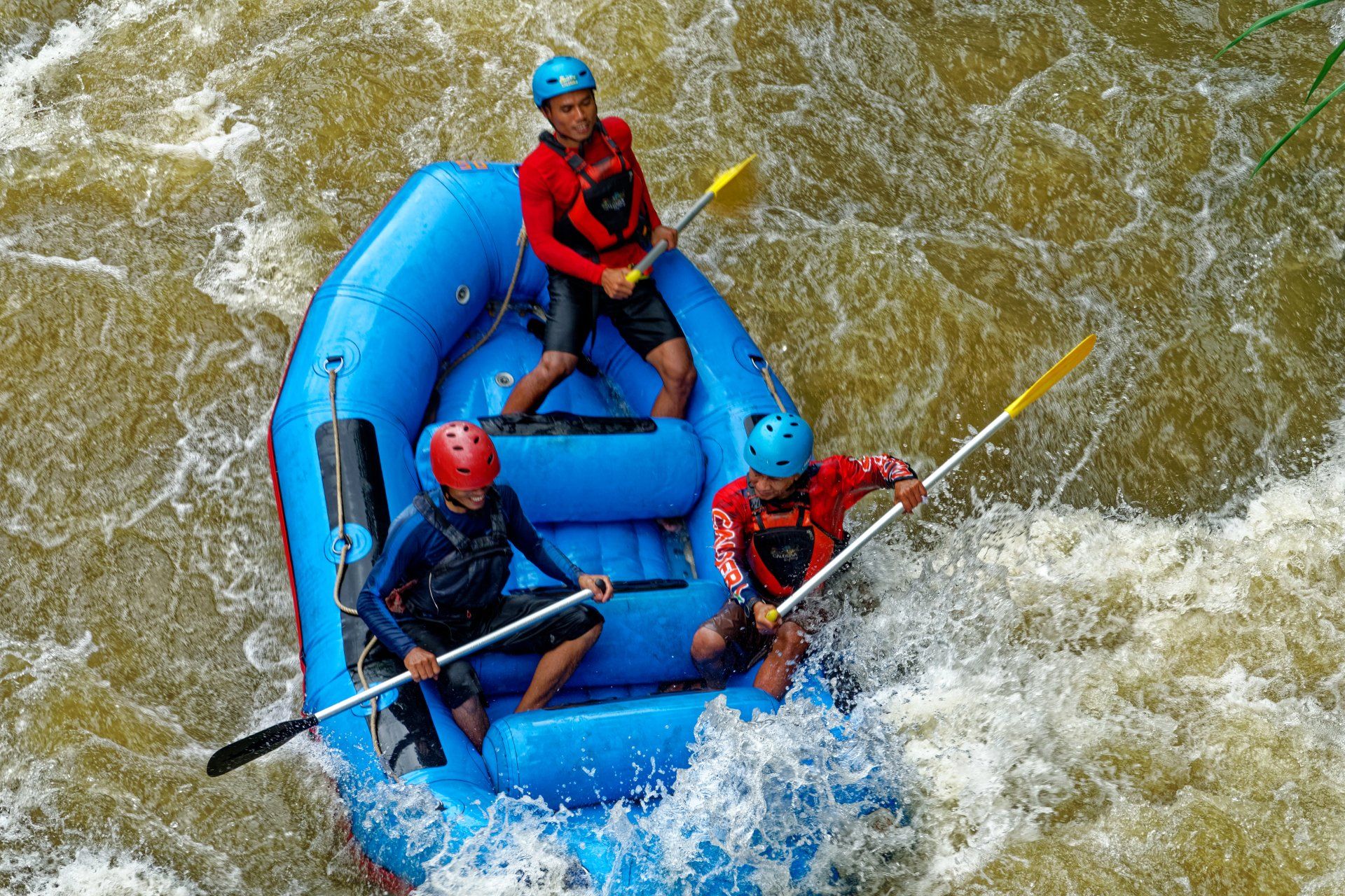 A group of people are rafting down a river in a blue raft.