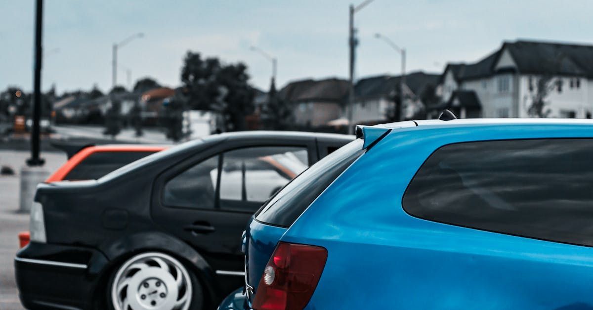 a blue car is parked next to a black car in a parking lot .