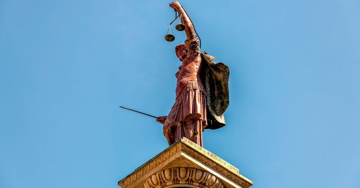 A statue of a woman holding scales of justice on top of a building.