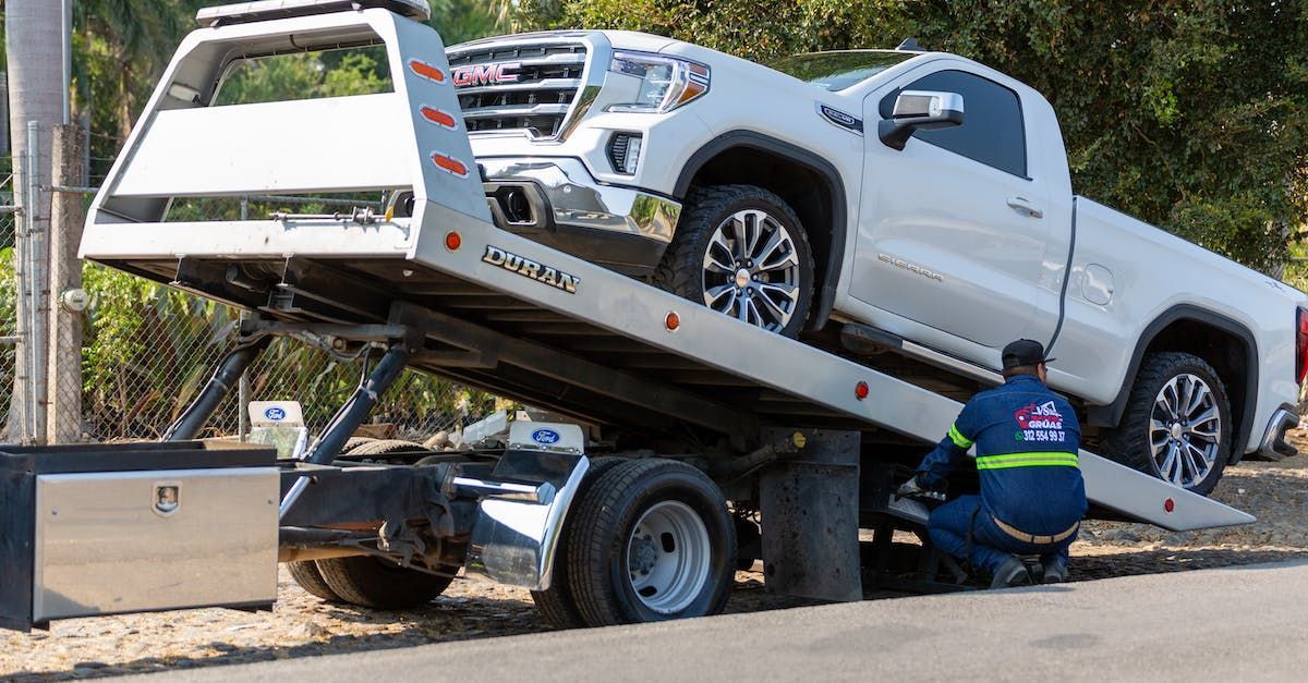 a white truck is being towed by a tow truck 