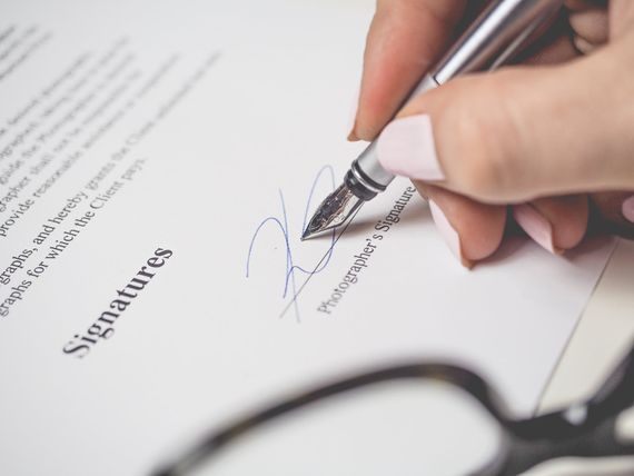 Una mano de una mujer firmando un contrata de investigación privada en Goodwin Detectives