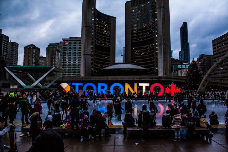 Uma multidão de pessoas está reunida em frente a uma placa que diz toronto