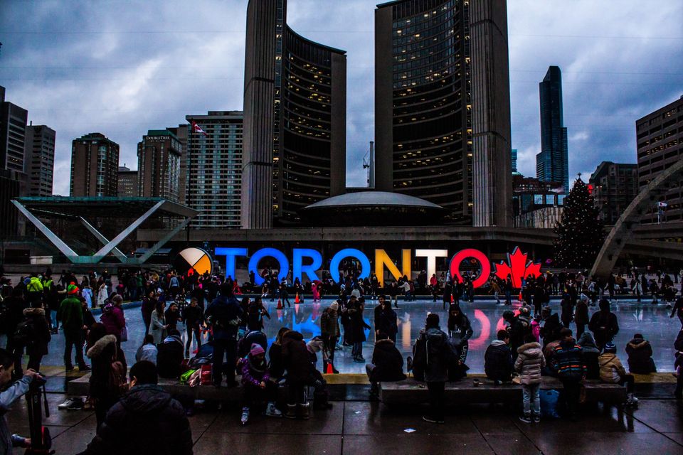 Uma multidão de pessoas está reunida em frente a uma placa que diz toronto