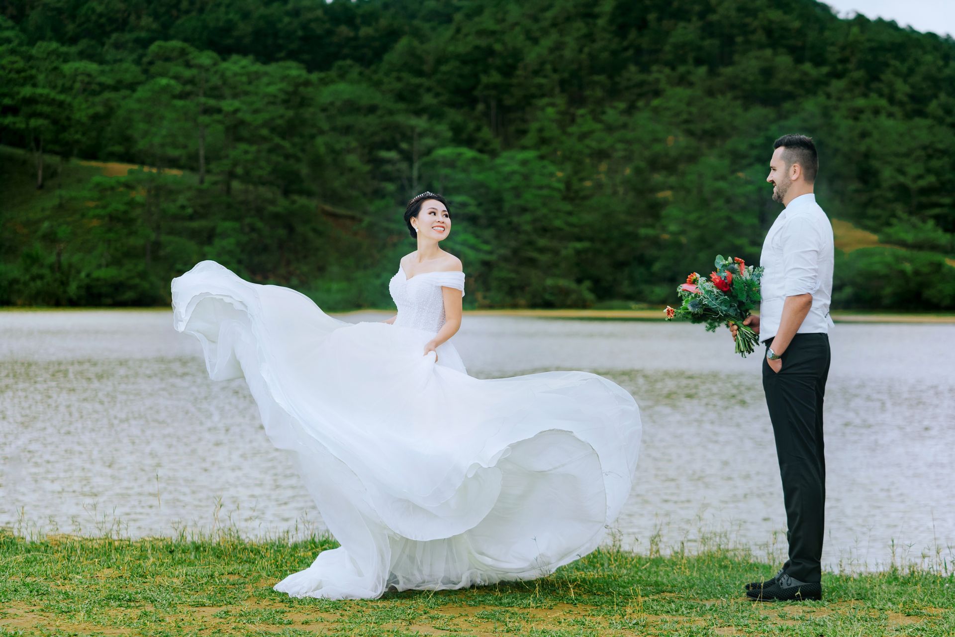 a bride and groom are posing for a picture in front of a lake.