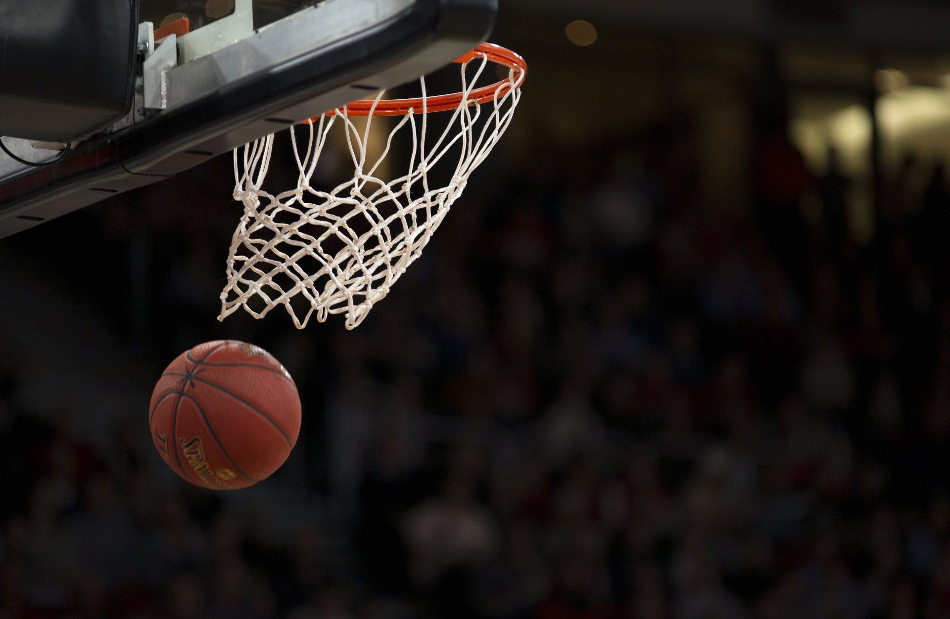 a basketball is going through the net of a basketball hoop .