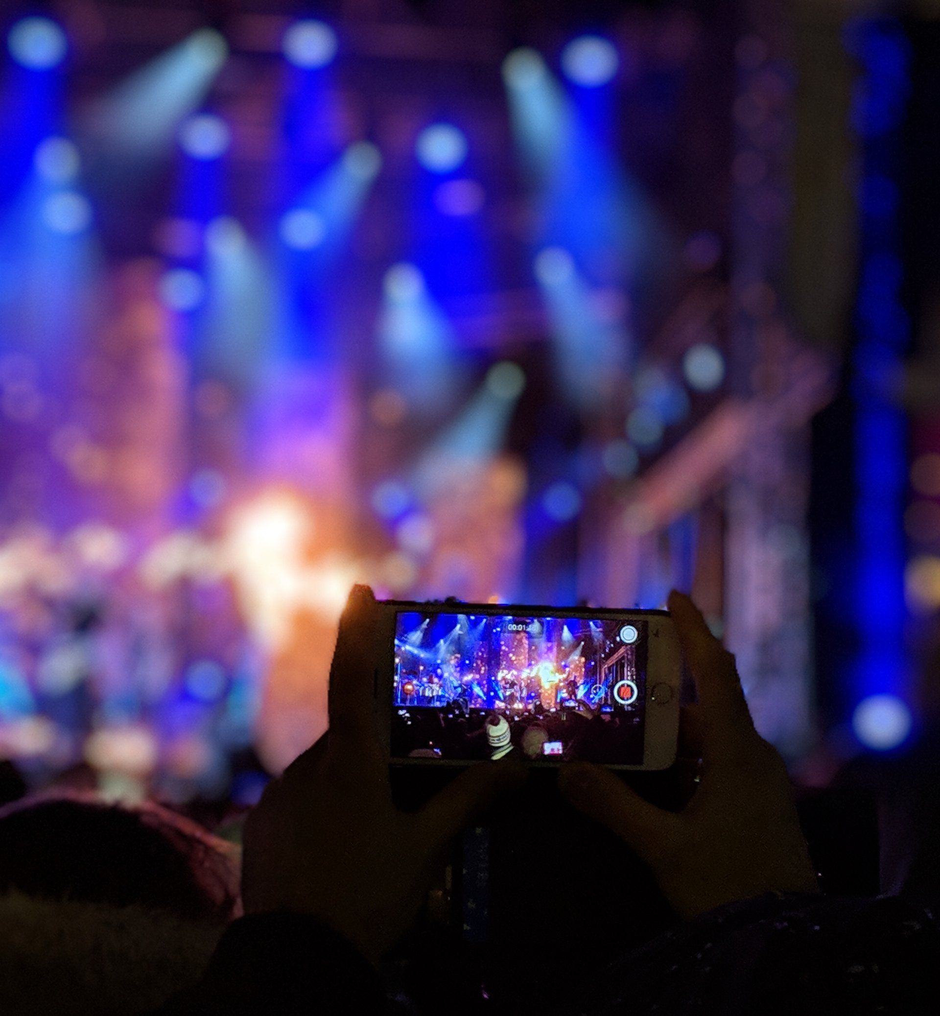 A person is taking a picture of a concert with a cell phone