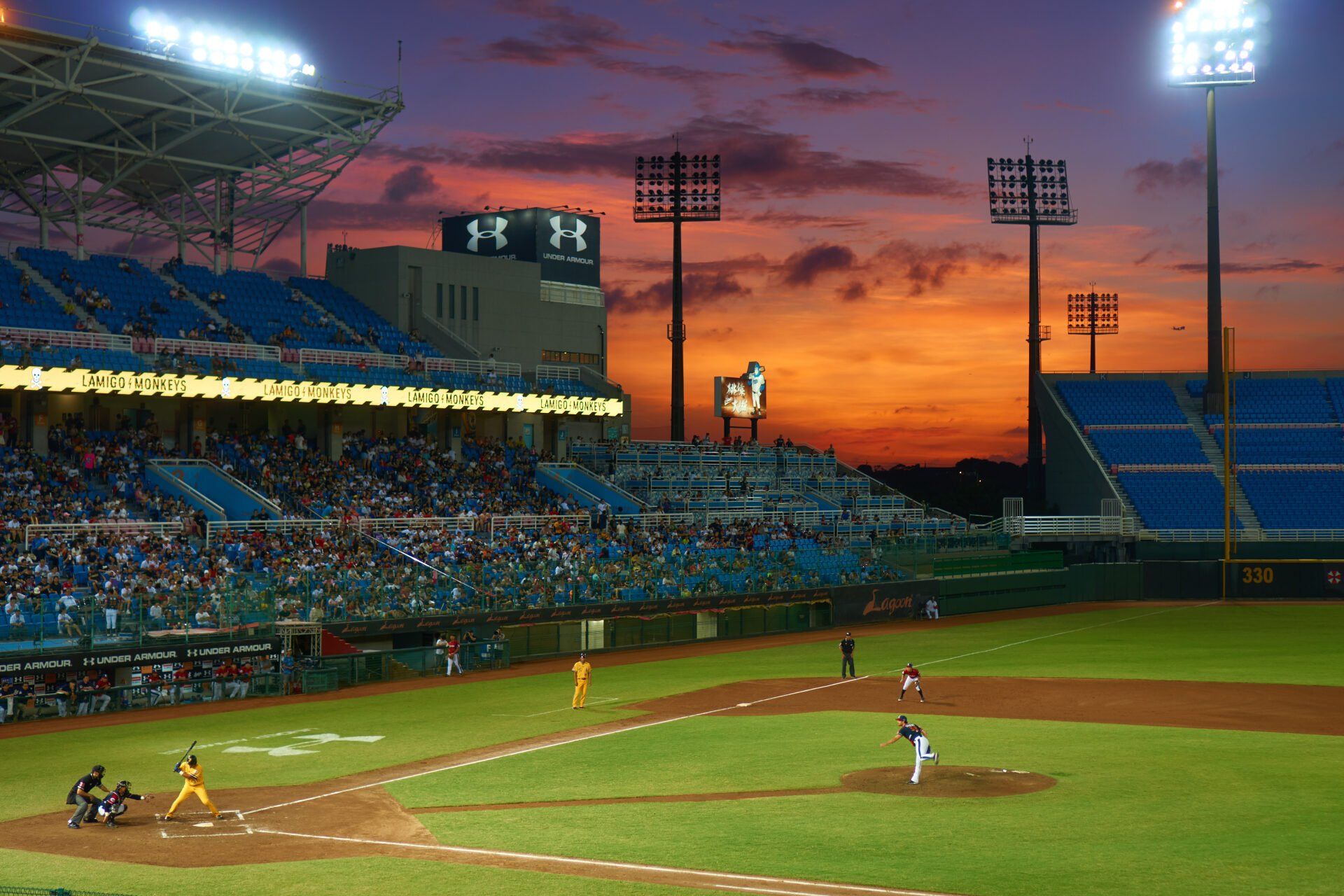 A baseball game is being played in a stadium at sunset. watching a better sports law.