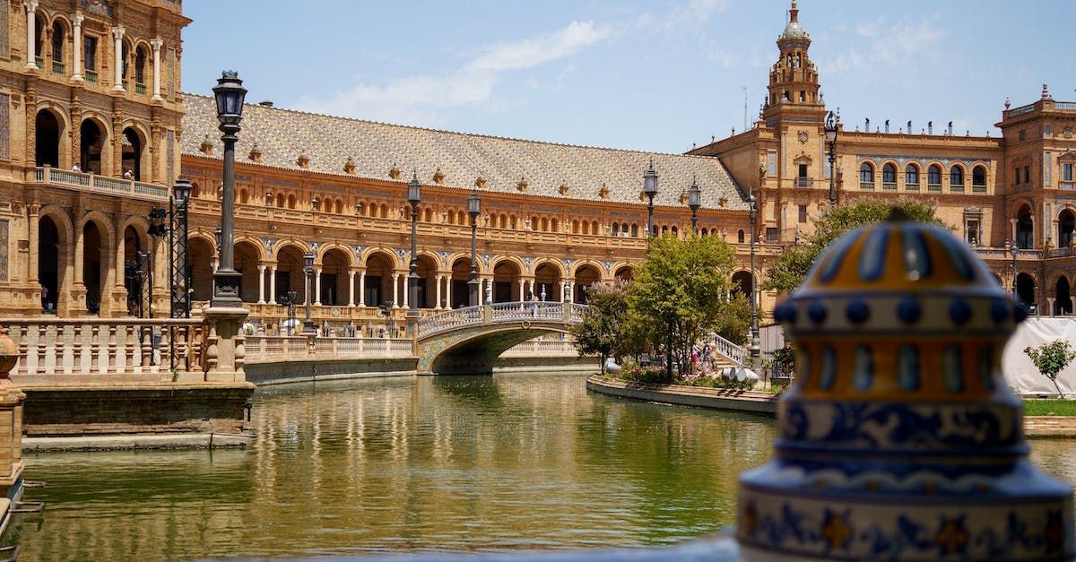 A bridge over a pond with a building in the background and a statue in the foreground.