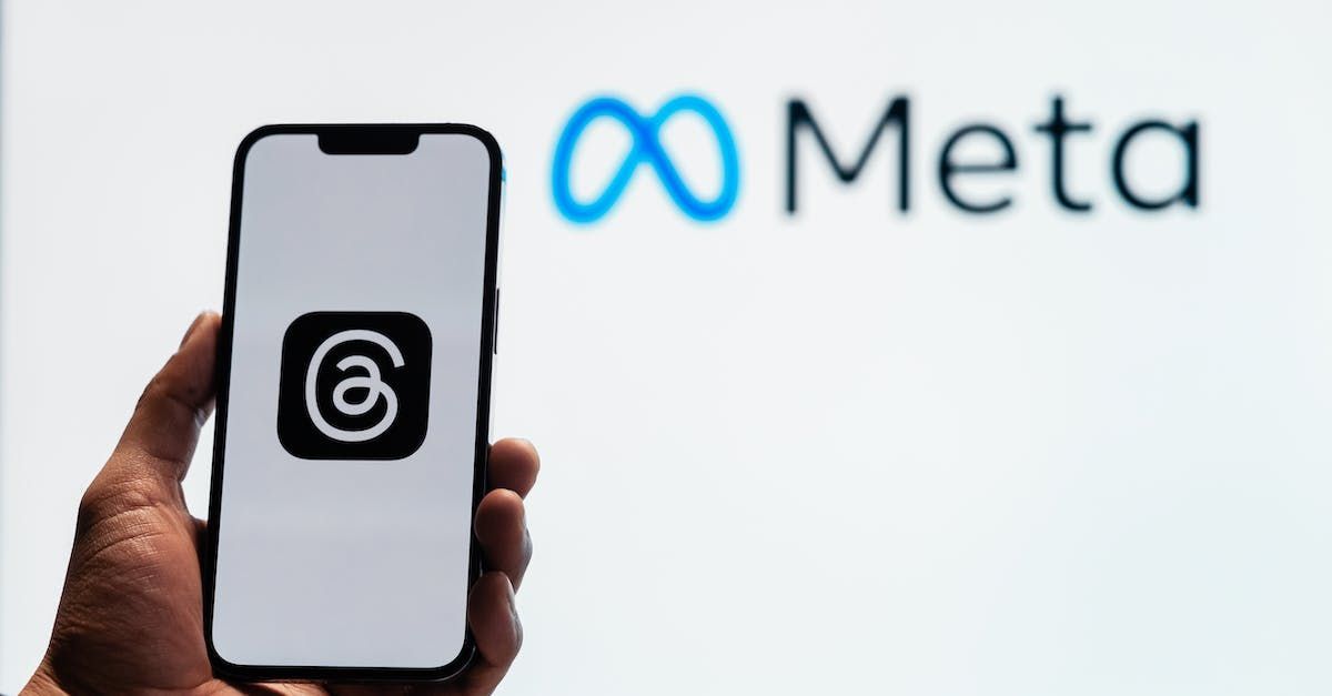 A person is holding a cell phone in front of a meta logo.