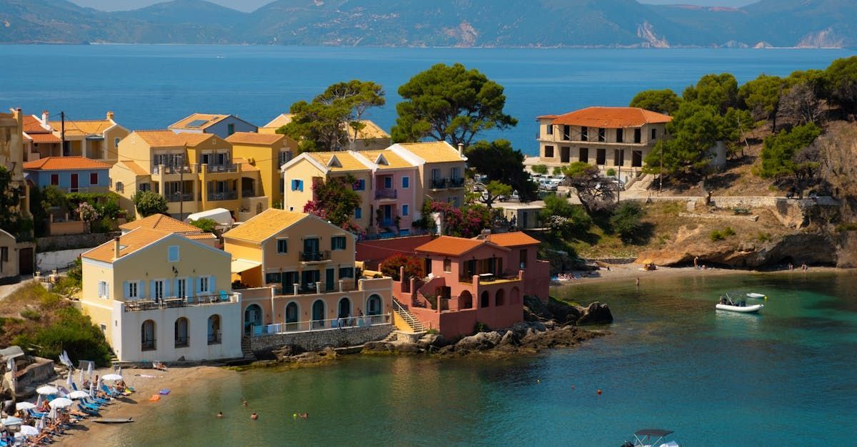 A group of houses are sitting on top of a hill next to a body of water.