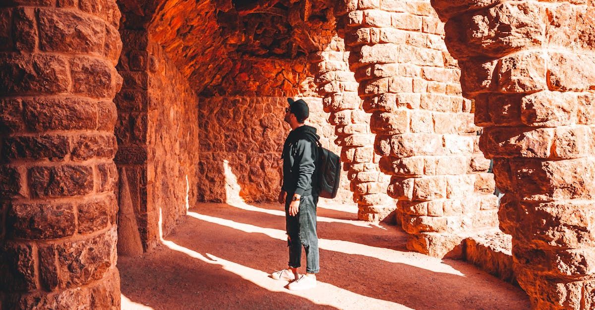 A man with a backpack is standing in a brick tunnel.