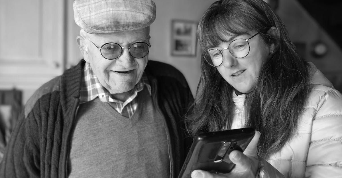 An elderly man and a young woman are looking at a tablet.