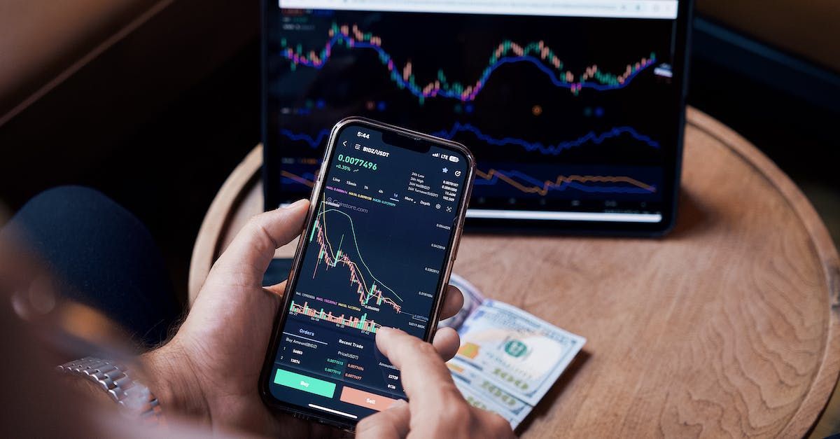 A person is holding a cell phone in front of a laptop.